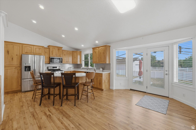 791 East Saddle Road Grantsville, UT 84029 - Photo 11 of 46 Kitchen with wood-finish flooring, light wood cabinetry, stainless steel appliances, and an island with seating
