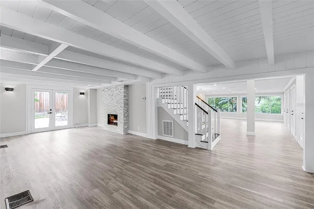 a view of an empty room with wooden floor fireplace and a window
