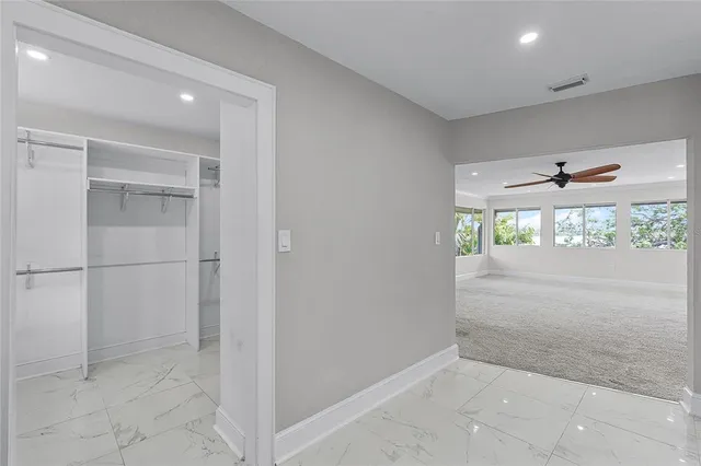an empty room with windows and ceiling fan