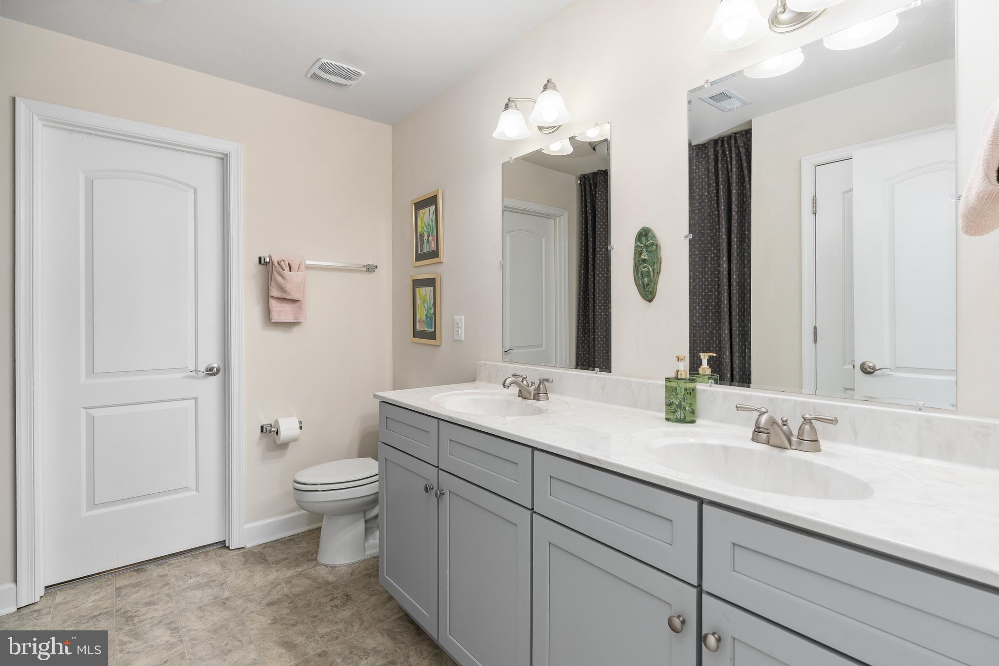109 12th Street Colonial Beach, VA 22443 - Photo 16 of 33 a bathroom with a double vanity sink a toilet and a mirror