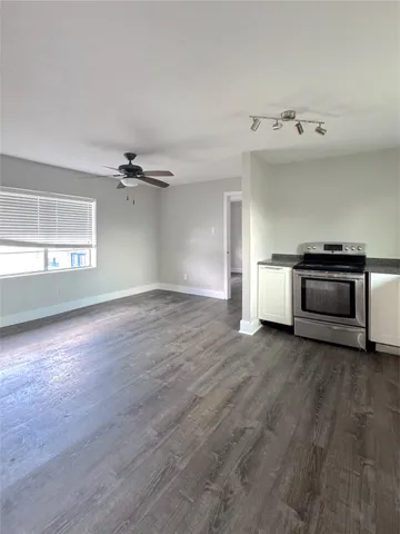 an empty room with wooden floor cabinet and windows