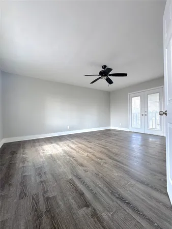 an empty room with wooden floor chandelier fan and windows