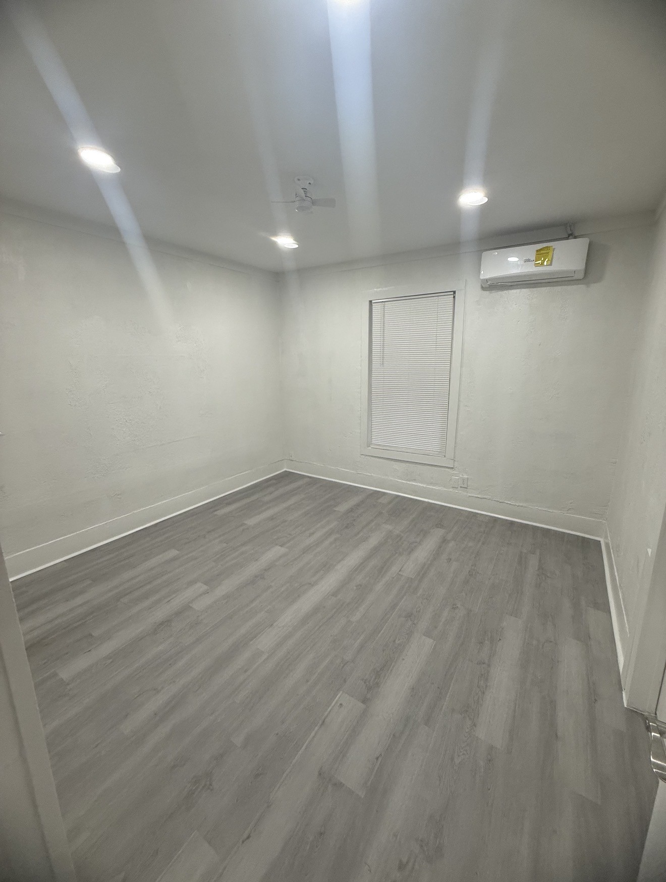 1009 Thomas Boulevard Port Arthur, TX 77640 - Photo 4 of 14 an empty room with wooden floor and windows