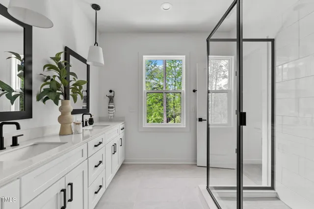 a spacious bathroom with a double vanity sink a mirror and a shower