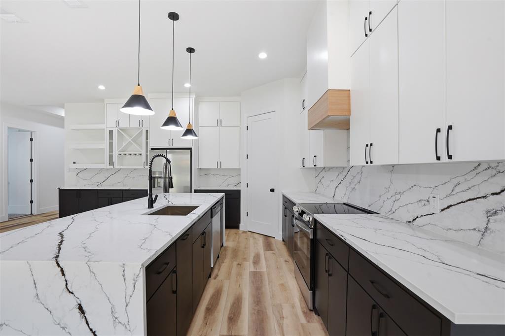 1111 Riverwood Road Dallas, TX 75217 - Photo 14 of 40 Modern kitchen featuring an expansive island with a built-in sink and pendant lighting