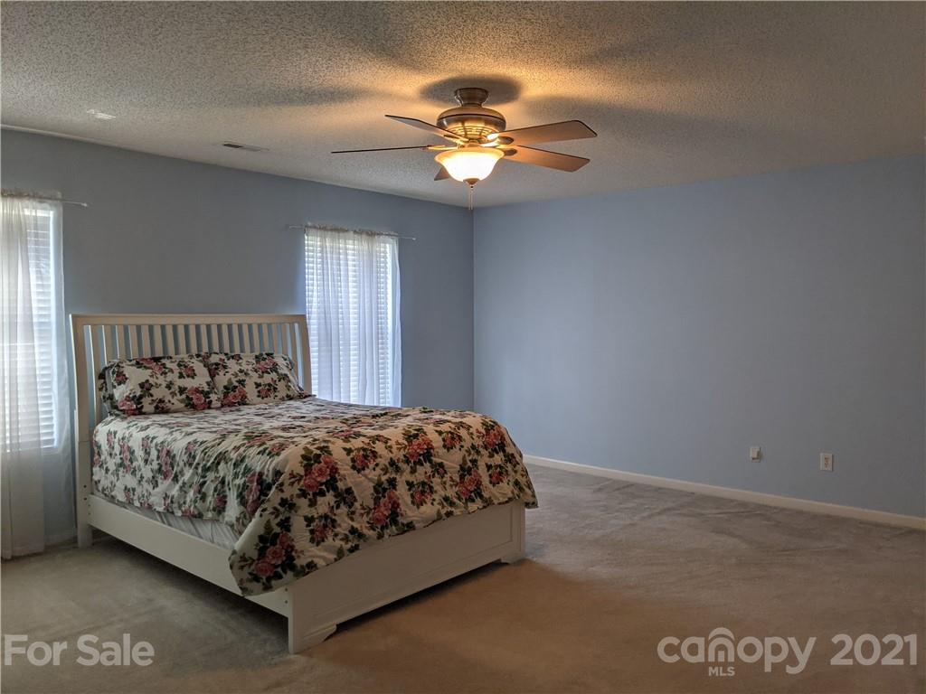 3111 Huntington Ridge Court Matthews, NC 28105 - Photo 22 of 34 a bedroom with a bed and a chandelier