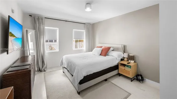 a bedroom with a bed and a flat tv screen on the dresser