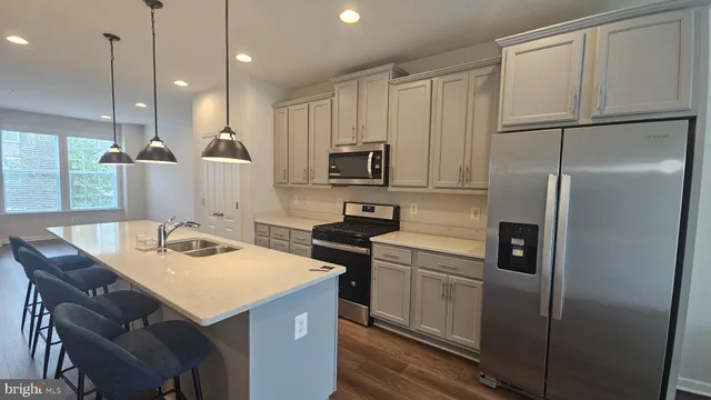 a kitchen with a refrigerator a sink a stove and chairs