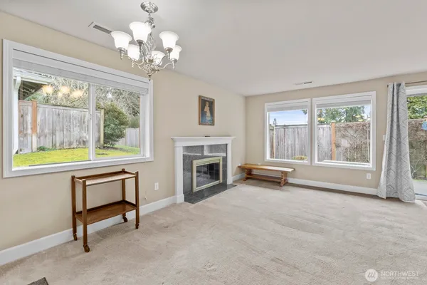 a view of a livingroom with a fireplace a chandelier and windows