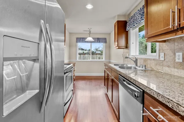 a kitchen with stainless steel appliances granite countertop a refrigerator a sink and a stove