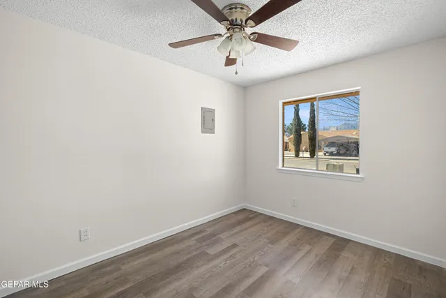 an empty room with a ceiling fan and wooden floor