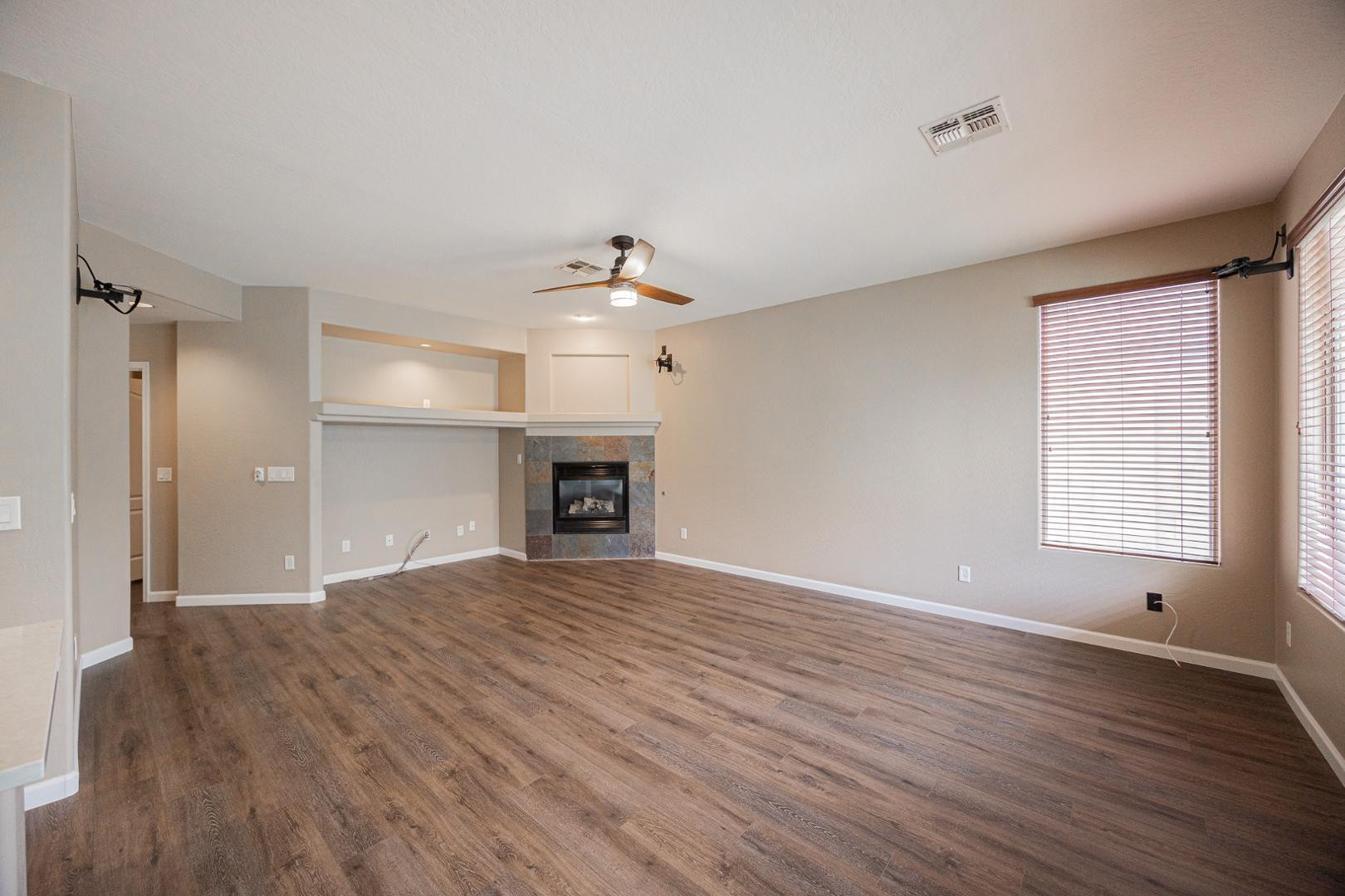 6539 West Jomax Road Phoenix, AZ 85083 - Photo 9 of 39 an empty room with wooden floor fireplace and windows