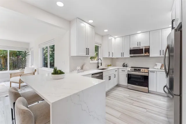 a kitchen with stainless steel appliances a stove a sink a microwave a refrigerator and cabinets