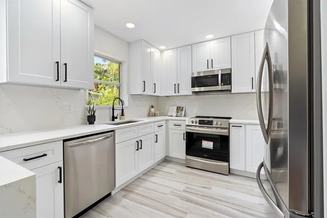 a kitchen with stainless steel appliances granite countertop a stove a sink and a refrigerator