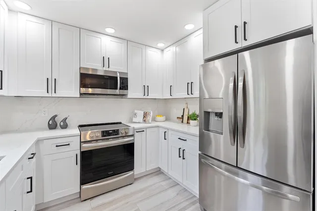 a kitchen with cabinets stainless steel appliances and wooden floor