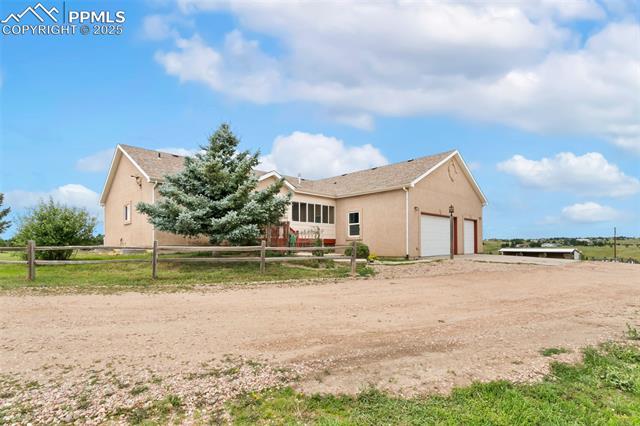 13775 Woodlake Road Elbert, CO 80106 - Photo 40 of 44 View of side of property featuring dirt driveway, stucco siding, and a garage