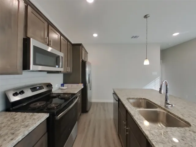 a kitchen that has a sink wooden cabinets stainless steel appliances and a counter top