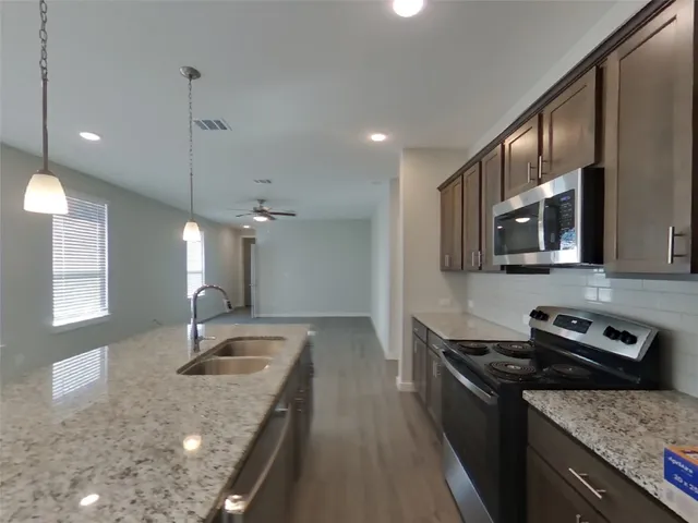 a kitchen with stainless steel appliances granite countertop a sink stove and refrigerator