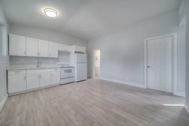 a view of a kitchen with white cabinets and wooden floor