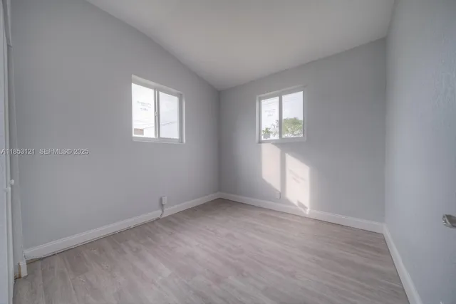 an empty room with wooden floor and closet area