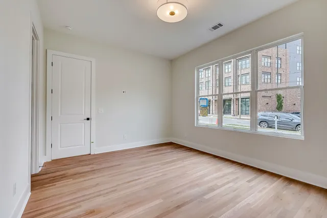 a view of an empty room with wooden floor and a window