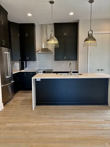 a kitchen with stainless steel appliances granite countertop a refrigerator a sink and a stove