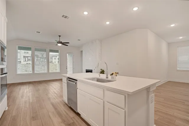 an empty room with wooden floor chandelier fan and windows