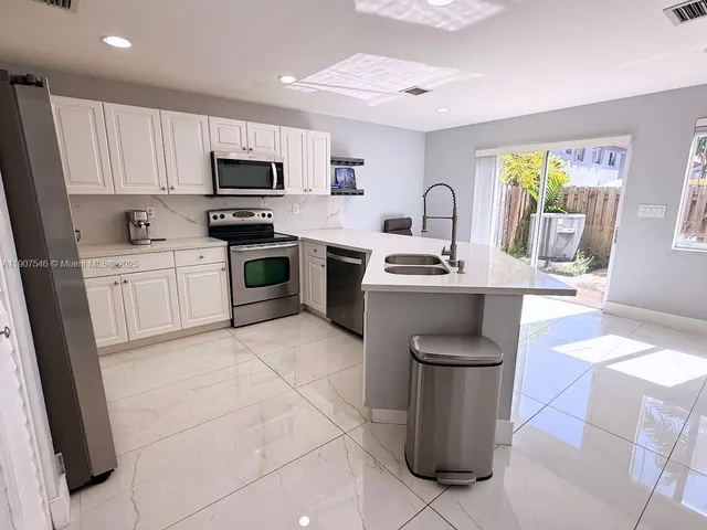 a kitchen with stainless steel appliances granite countertop a sink a stove top oven a counter space and cabinets