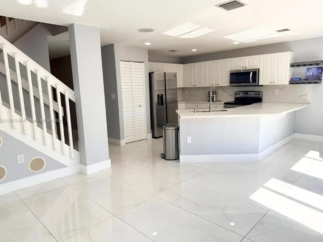 a living room with stainless steel appliances kitchen island granite countertop a refrigerator and a stove top oven