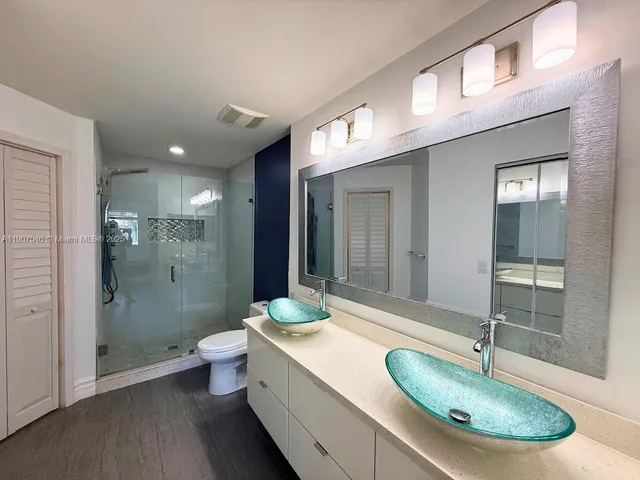 a bathroom with a granite countertop sink a toilet a mirror and shower