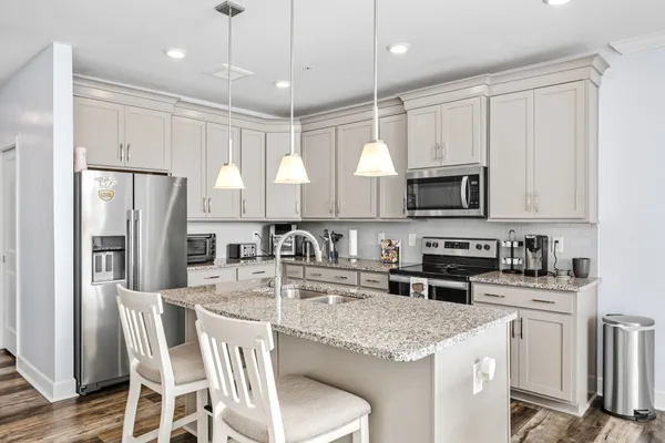 a kitchen with stainless steel appliances granite countertop a white cabinets stove a sink and a refrigerator