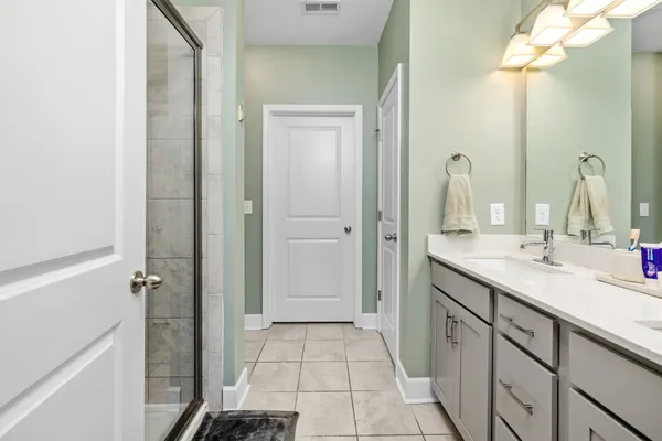 a spacious bathroom with a double vanity sink a mirror and a shower