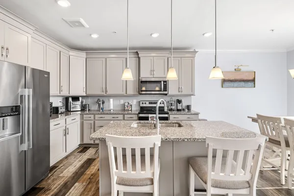 a kitchen with kitchen island granite countertop a sink a stove a refrigerator cabinets and a dining table