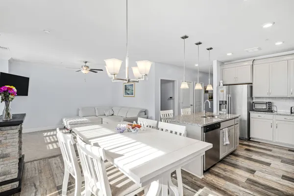 a large kitchen with granite countertop a stove a sink a dining table and chairs