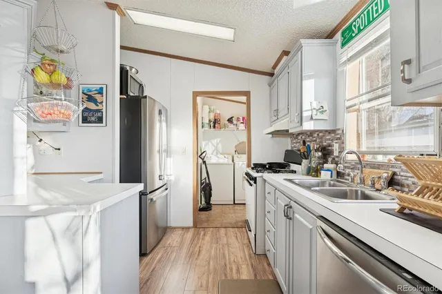 a kitchen with stainless steel appliances granite countertop a refrigerator a stove a sink and dishwasher with wooden floor