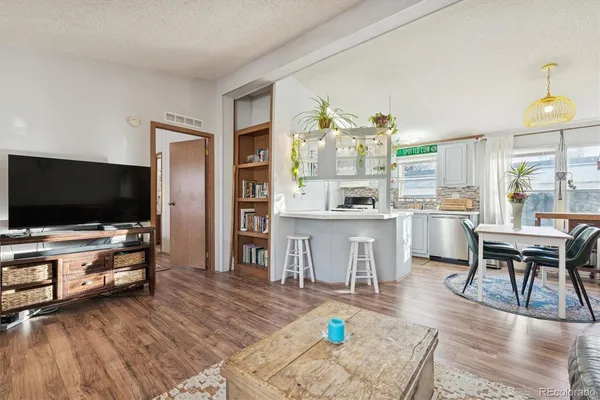 a living room with stainless steel appliances furniture and a flat screen tv