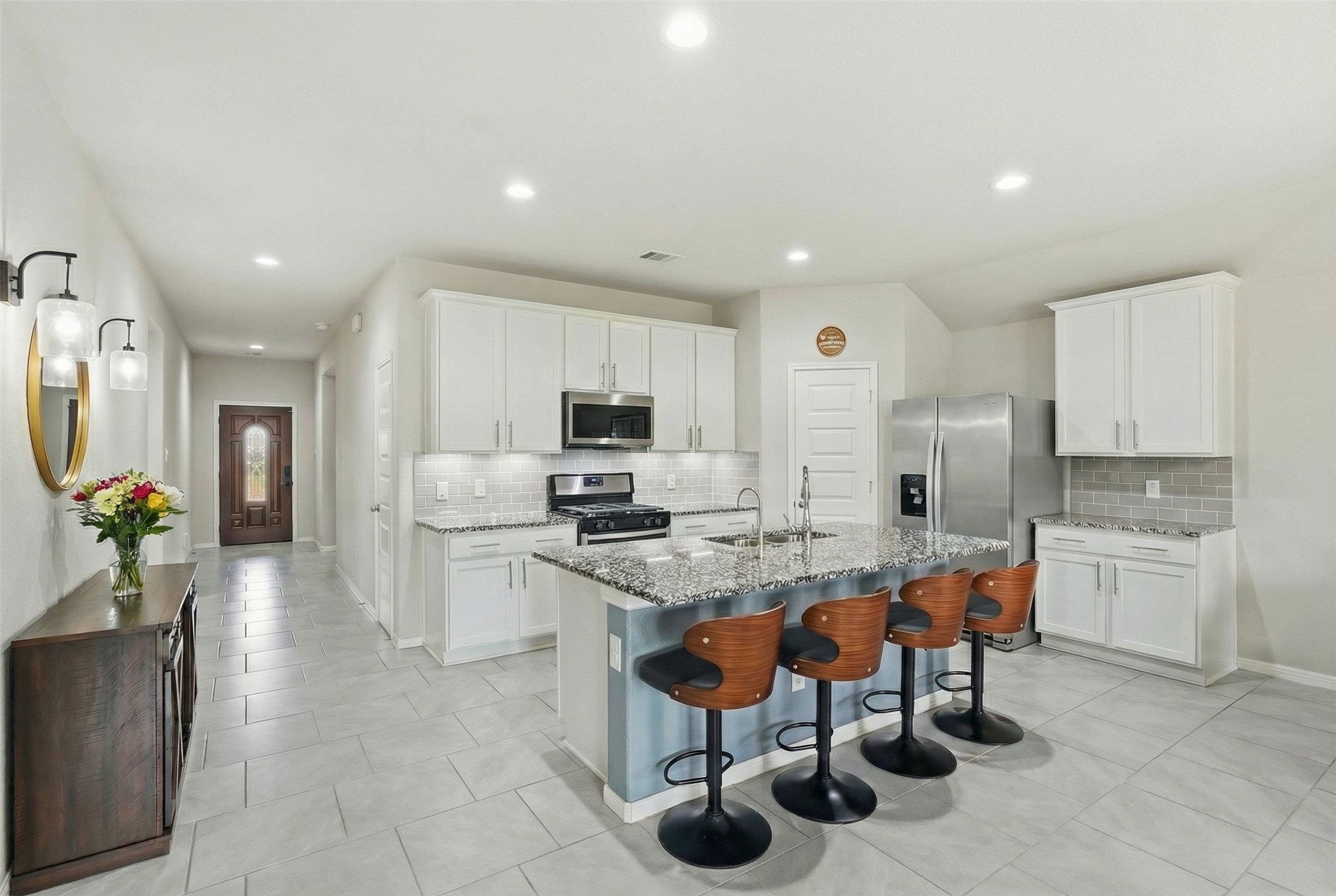 a kitchen with stainless steel appliances kitchen island granite countertop a table chairs sink and cabinets