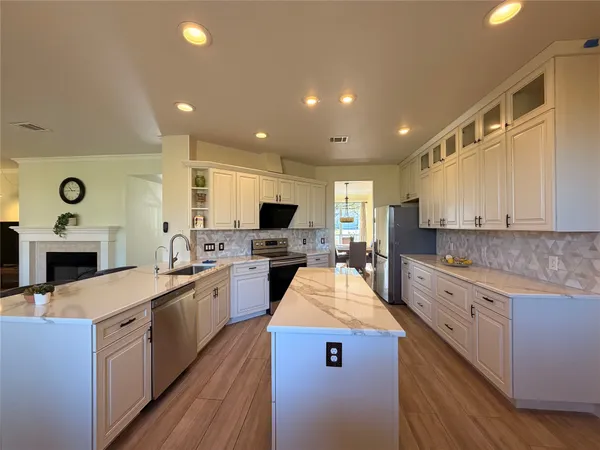 a large kitchen with stainless steel appliances granite countertop lots of counter top space a sink and a fireplace
