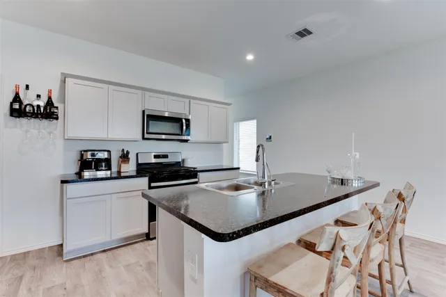 a kitchen with stainless steel appliances granite countertop sink stove and refrigerator