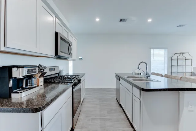 a kitchen with granite countertop a sink a stove and cabinets