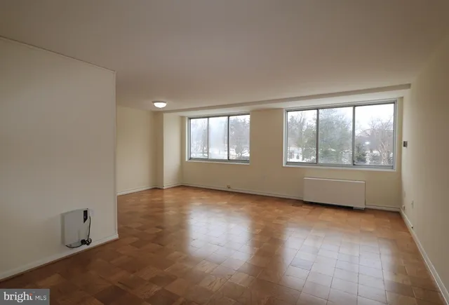 a view of an empty room with a window and wooden floor