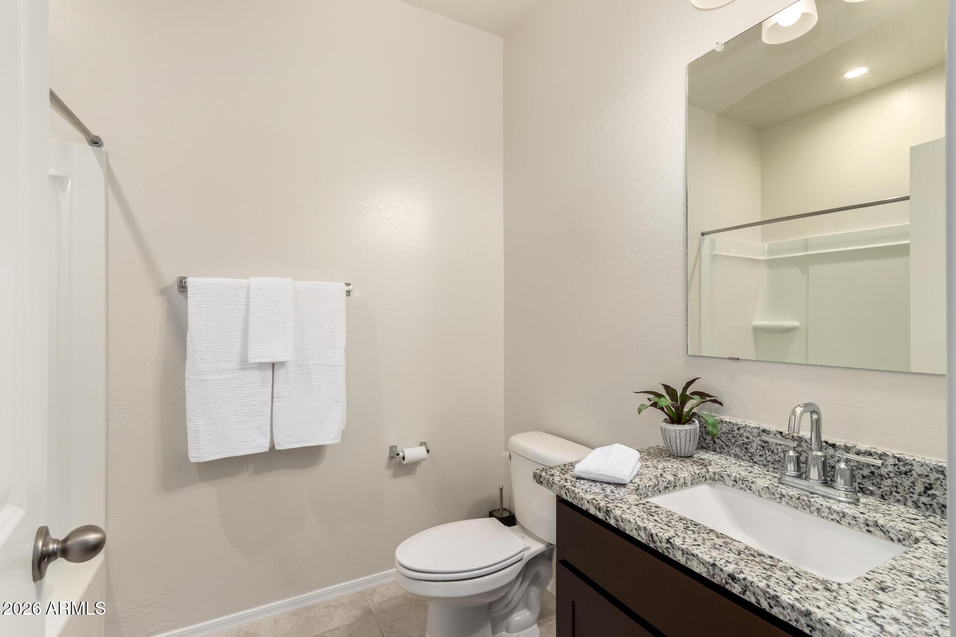 5065 East Emery Road San Tan Valley, AZ 85143 - Photo 21 of 33 a bathroom with a granite countertop sink a toilet and a mirror