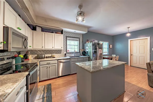 a large kitchen with granite countertop a sink dishwasher stove and cabinets with wooden floor