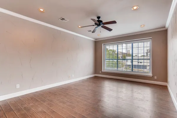 a view of an empty room with wooden floor and a window