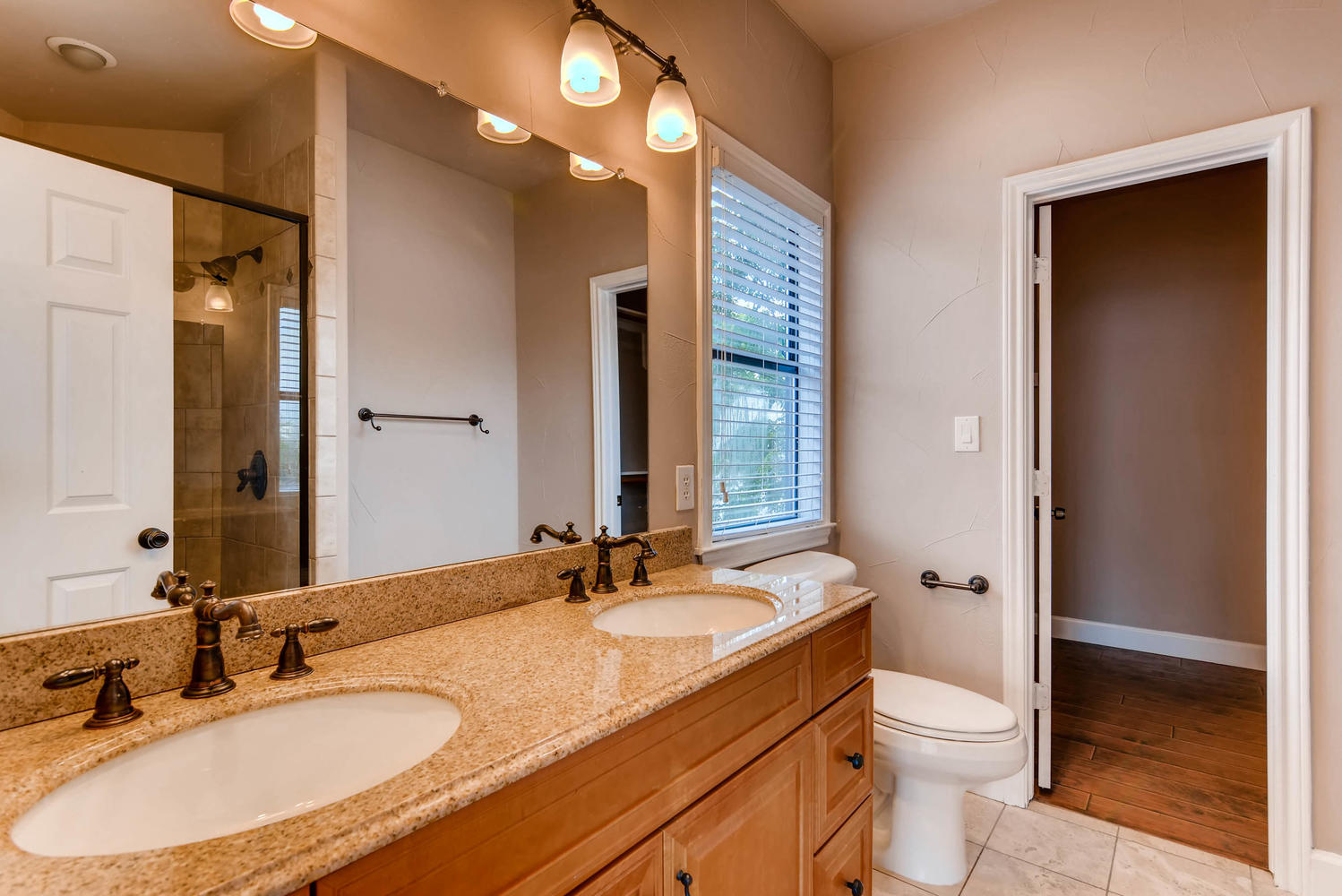 906 Juniper Street Austin, TX 78702 - Photo 17 of 28 a bathroom with a granite countertop sink toilet a large mirror a vanity and shower
