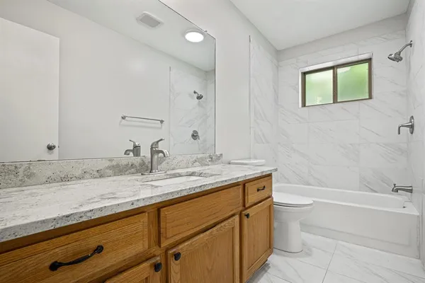 a bathroom with a granite countertop sink toilet and bathtub