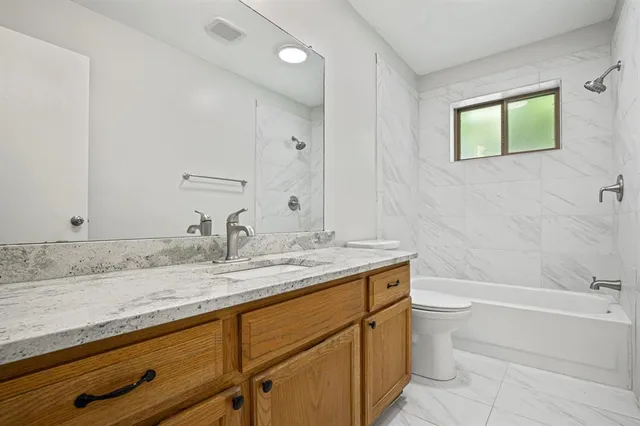 a bathroom with a granite countertop sink toilet and bathtub