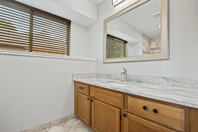 a bathroom with a granite countertop sink and a window