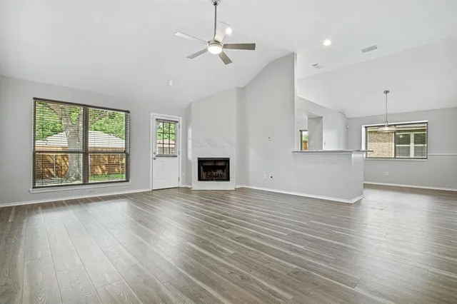 an empty room with wooden floor fireplace and windows