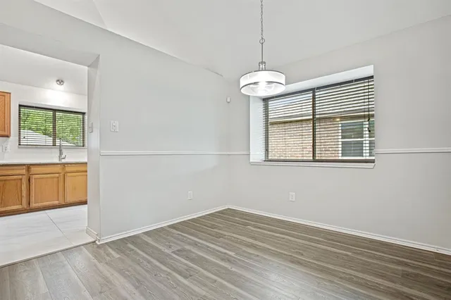 a view of empty room with wooden floor and window